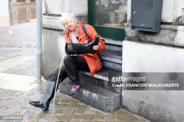 Woman removes water from her boot on July 15, 2021 in the Belgian city of Verviers, after heavy rains and floods lashed western Europe, killing at...
