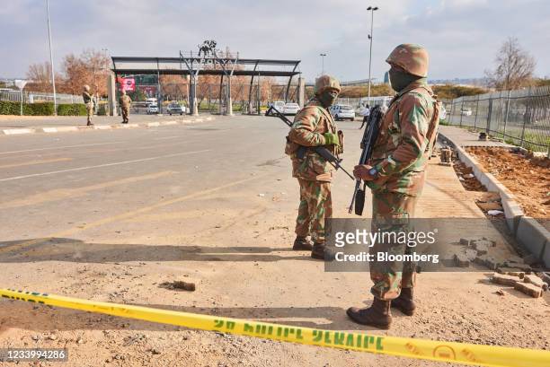Armed soldiers from the South African National Defence Force patrol at the gates of Maponya Mall following rioting in the Soweto district of...