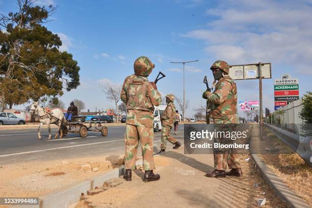 Armed soldiers from the South African National Defence Force patrol close to the Maponya Mall following rioting in the Soweto district of...