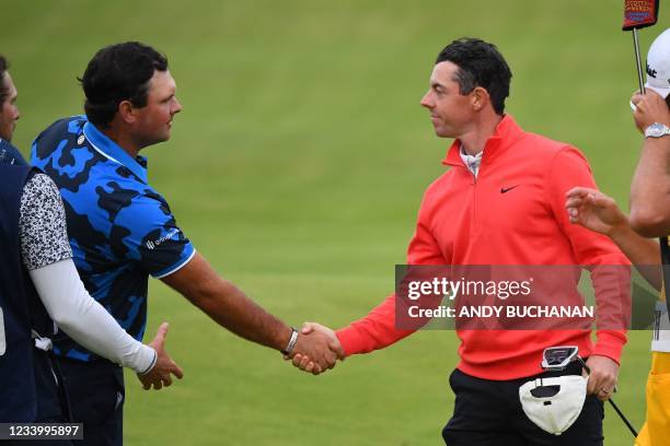 Northern Ireland's Rory McIlroy shakes hands with US golfer Patrick Reed on the 18th green after their first rounds on day one of The 149th British...