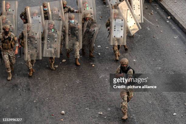 July 2021, Lebanon, Beirut: A Lebanese soldier aims at protestors as he leads his colleagues into a counter-attack during clashes after Lebanon's...