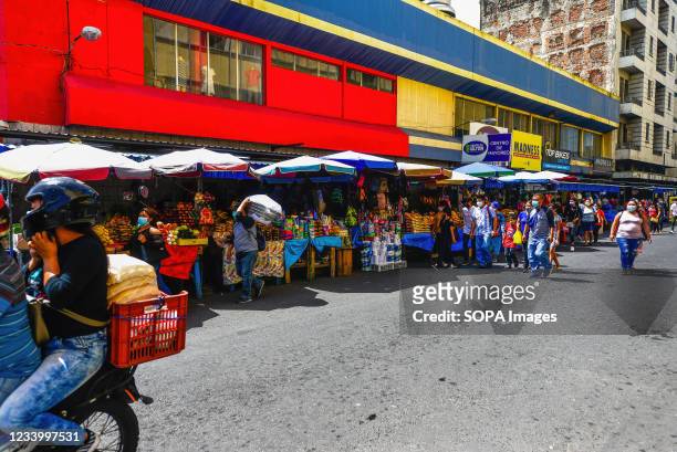 People walk by a market, selling produce in downtown. El Salvador´s Congress approved new covid-19 restrictions to cancel public gatherings,...
