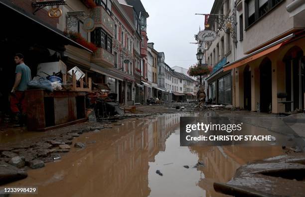 Resident stands next to damaged furnitures in a flooded street in Bad Neuenahr-Ahrweiler, western Germany, on July 15, 2021. - German authorities...