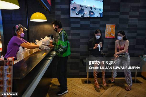 GrabFood delivery driver picks up orders of the limited edition "BTS Meal" as two fans of the K-pop band BTS wait for their takeaway meal from a...