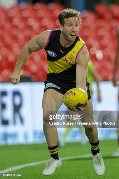 Kane Lambert hand passes the ball during the 2021 AFL Round 18 match between the Richmond Tigers and the Brisbane Lions at Metricon Stadium on July...