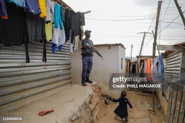 Child runs past a member of the South African Police Services while keeping watch during a joint operation with South African Defence Force to...