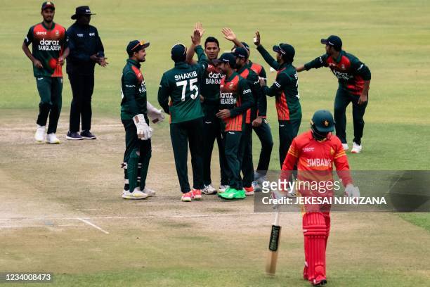 Bangladesh players celebrate as Zimbabwe's Tadiwanashe Marumani walks off the field after loosing his wicket during the first One-Day International...
