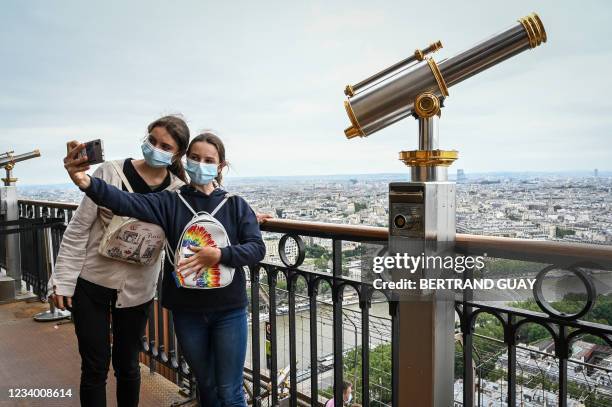 Visitors take a selfie picture as they visit the Eiffel Tower in Paris, on July 16, 2021. The Eiffel Tower reopened to visitors on July 16 after nine...