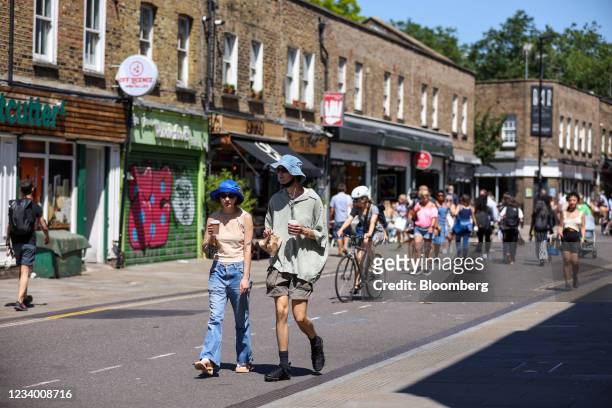 People carry take-away coffee at Broadway Market in Hackney, London, U.K., on Friday, July 16, 2021. Al fresco dining will become the norm in Britain...