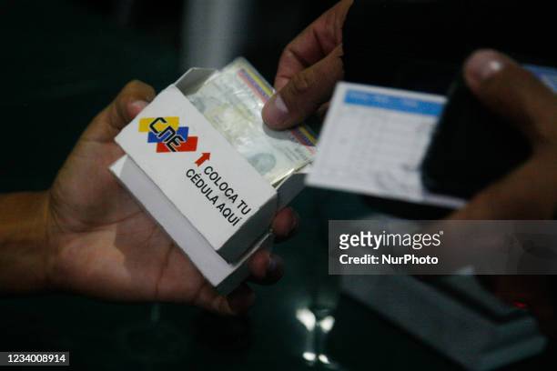 Man removes his identity card during a registration and data update day at the National Electoral Council , amid the Coronavirus pandemic in Caracas,...