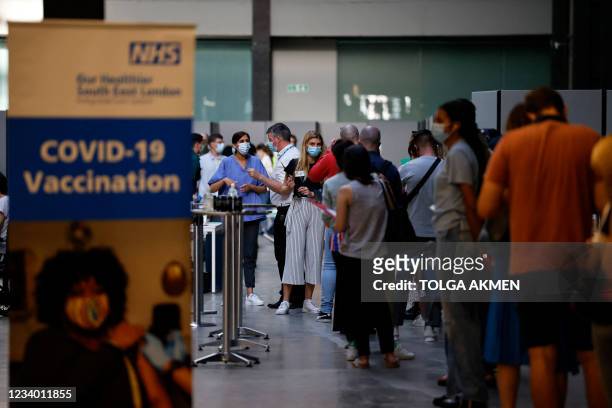 Members of the public queue to receive the Pfizer-BioNTech Covid-19 vaccine in the Turbine Hall at a temporary Covid-19 vaccine centre at the Tate...