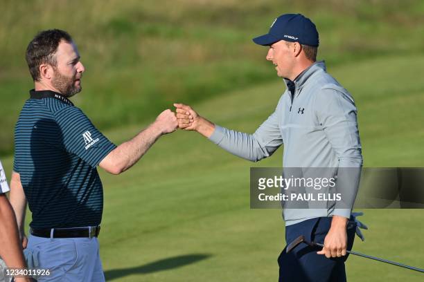 South Africa's Branden Grace fist bumps US golfer Jordan Spieth after finishing their second round on day 2 of The 149th British Open Golf...
