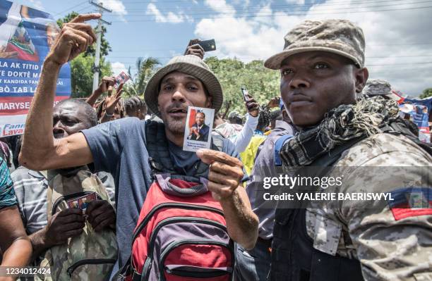 Police try to hold people back as supporters cheer and surround an ambulance carrying former Haitian President Jean-Bertrand Aristide after he...