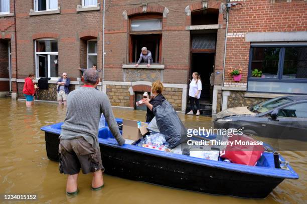 People use a boat to bring water and food to neigbours following a severe storm on July 16, 2021 in 'Rue de Tilff' in Angleur, a district from Liège,...