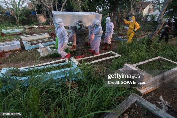 Health workers wearing personal protective equipment carry a coffin of a Covid-19 victim, who died at home during self-isolation after the local...