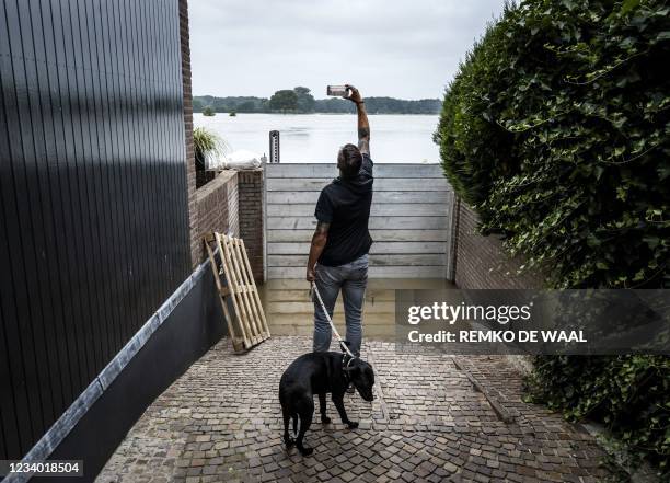 Man takes a picture before evacuating in Arcen on July 17 following heavy rains and floods in the in North Limburg which has caused a lot of damage....