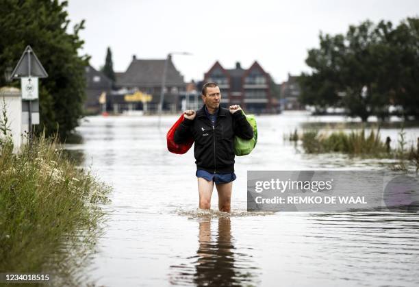 Man leaves a flooded house in Arcen on July 17 following heavy rains and floods in the in North Limburg which has caused a lot of damage. - The death...