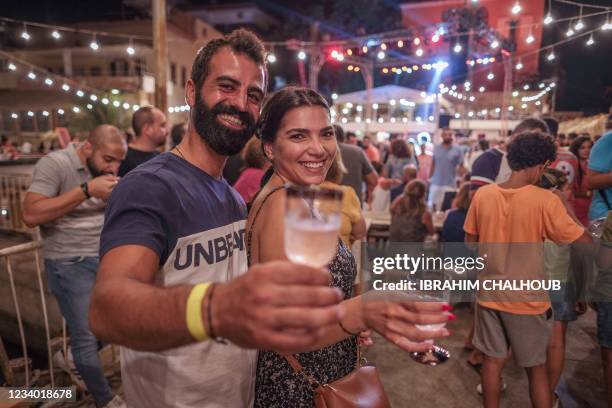 People pose for a picture during the annual Beer, Wine, and Seafood Festival in Lebanon's northern coastal city of Batroun, late on July 16, 2021.