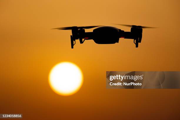 Quadcopter drone hovering during a flight in front of the sun. The flying drone is seen as a dark silhouette against the spectacular colorful sunset...