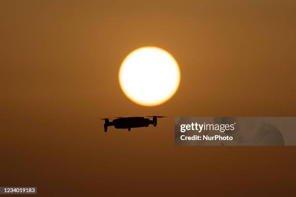 Quadcopter drone hovering during a flight in front of the sun. The flying drone is seen as a dark silhouette against the spectacular colorful sunset...