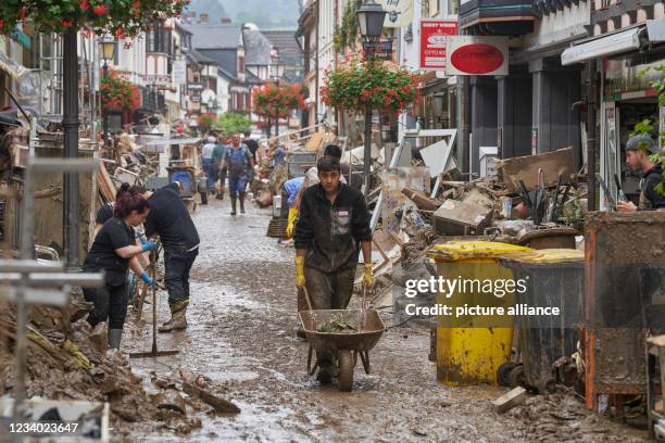 July 2021, Rhineland-Palatinate, Ahrweiler: Residents and shopkeepers are trying to clear mud from their homes and move unusable furniture outside....