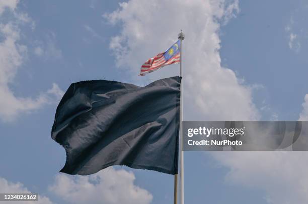 Black flag waves with the Malaysia flag during a protest in Kuala Lumpur, Malaysia on July 17, 2021. The #BlackFlag protest organizer whom...