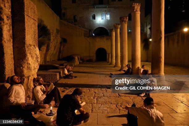 Orthodox Jewish men pray and read from the book of Eicha at the Jewish Quarter in Jerusalem's Old City on July 17 during the annual Tisha B'Av...