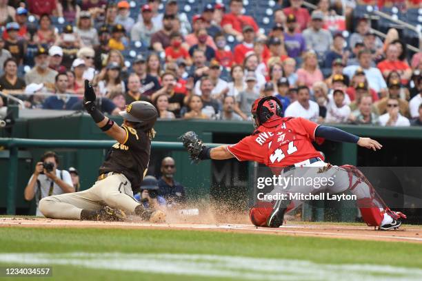 Fernando Tatis Jr. #23 of the San Diego Padres slides by Rene Rivera of the Washington Nationals to score on a Manny Machado fly out in the first...