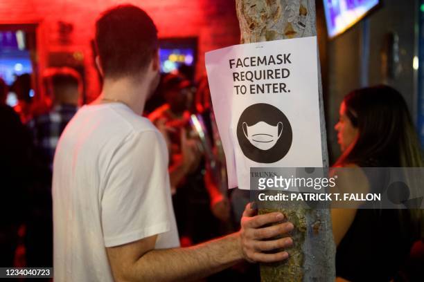 Face mask signage is displayed outside the Trunks bar after midnight early Sunday morning on July 18, 2021 in West Hollywood, California. - Wearing a...