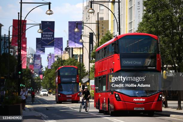 Cyclist rides around a London bus on Oxford Street on July 18, 2021 in London, England. On Monday, England will drop nearly all remaining...