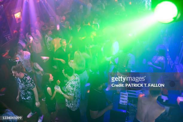 People dance and drink before a reimposed indoor mask mandate at the Trunks bar Saturday night before midnight on July 17, 2021 in West Hollywood,...
