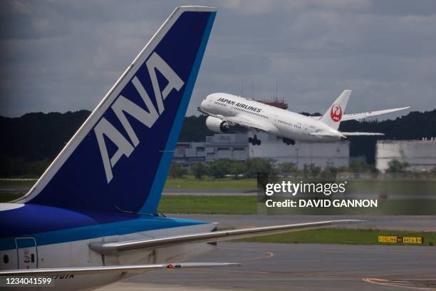 Japan Airlines passenger plane takes off past another from All Nippon Airways at Tokyo's Narita International Airport in Narita, Chiba Prefecture on...