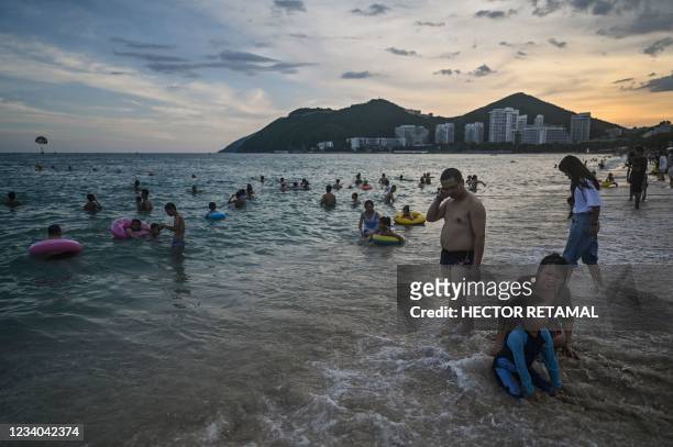People enjoy bathing at Dadonghai beach in Sanya on China's tropical Hainan Island on July 18, 2021.