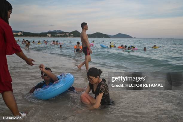 People enjoy bathing at Dadonghai beach in Sanya on China's tropical Hainan Island on July 18, 2021.