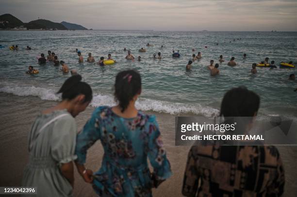 People swim at Dadonghai beach in Sanya on China's tropical Hainan Island on July 18, 2021.