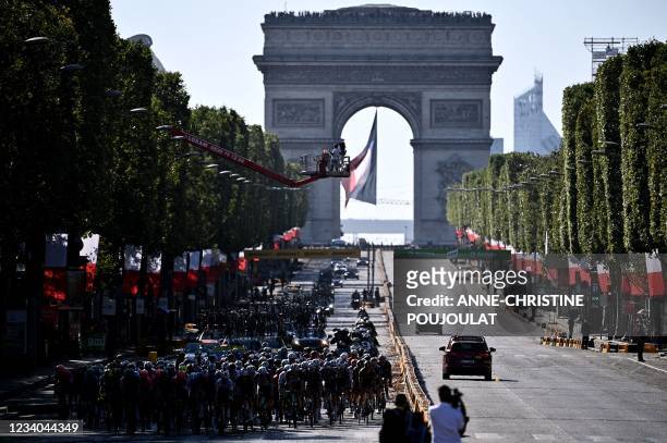 The pack rides on the Champs Elysee avenue with the Arc de Triomphe in the background during the 21th and last stage of the 108th edition of the Tour...
