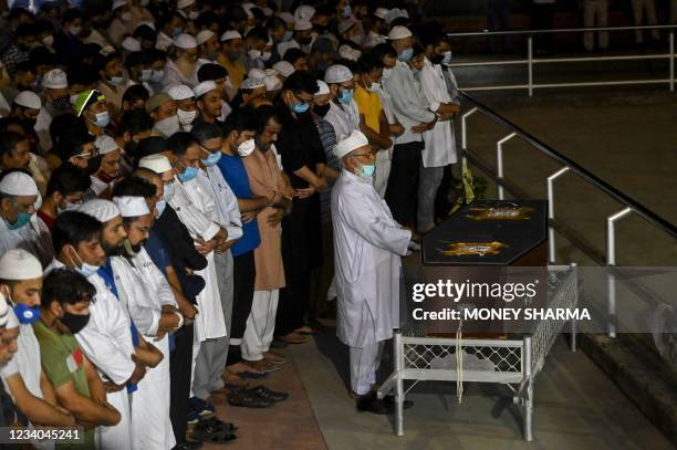 Mourners pray near the mortal remains of Reuters journalist Danish Siddiqui before his burial in New Delhi on July 18 after the Pulitzer...