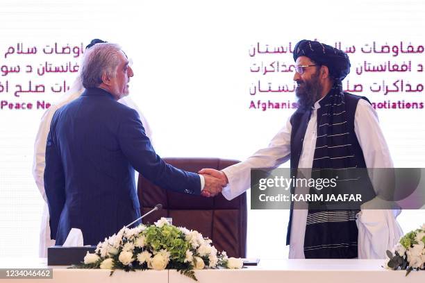 The head of Afghanistan's High Council for National Reconciliation Abdullah Abdullah shakes hands with the leader of the Taliban negotiating team...