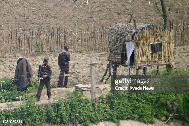 Photo taken from the Chinese border city of Dandong on June 7 shows North Korean soldiers in the fields in Uiju county.