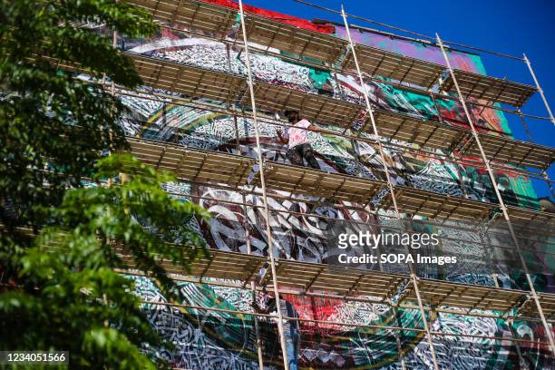 Palestinian artist, Belal Khaled and his team putting the final touches to a graffiti painting on a building wall destroyed by Israeli airstrike in...