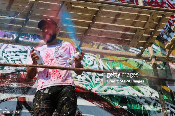 Palestinian artist, Belal Khaled uses spray paint to make final touches to a graffiti painting on a building wall destroyed by Israeli airstrike in...