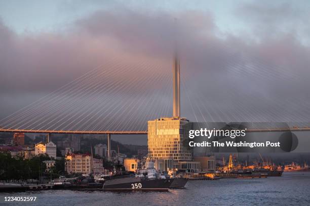 Military battleships and the Golden bridge on the sunset in Vladivostok, Russia on May 30, 2021.
