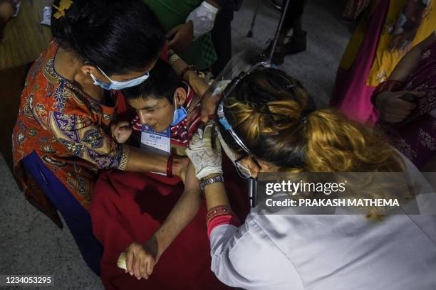 Health worker inoculates a physically challenged woman with a dose of the US Johnson and Johnson vaccine against the Covid-19 coronavirus at the...