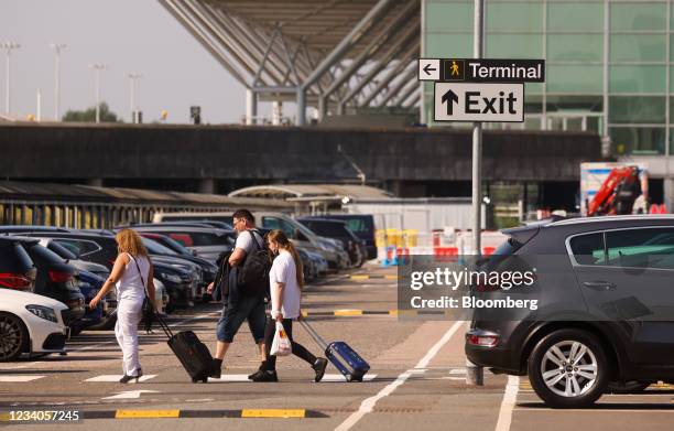 Passengers pull luggage towards the terminal building at London Stansted Airport, operated by Manchester Airport Plc, in Stansted, U.K., on Monday,...