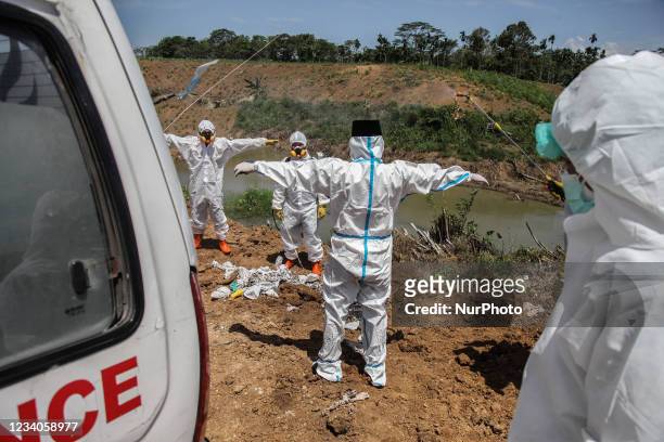 Funeral workers spray disinfectant during burying Covid-19 victims at a cemetery on July 19, 2021 in Medan, Indonesia. Indonesia has become the new...