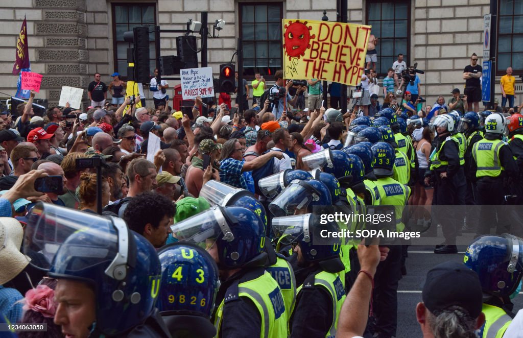 Police officers in riot gear form a cordon to prevent the...