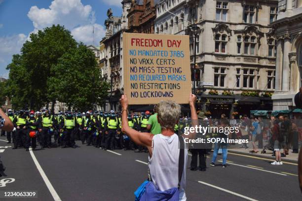 Protester holds up a Freedom Day anti-restrictions placard in front of the police during the demonstration in Parliament Street. Demonstrators...