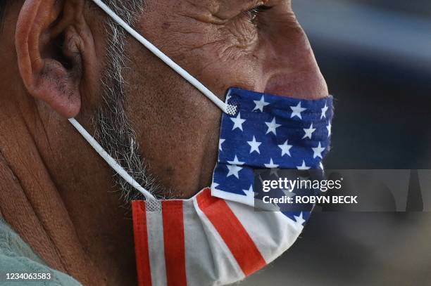 Man wears an American flag face mask on July 19, 2021 on a street in Hollywood, California, on the second day of the return of the indoor mask...