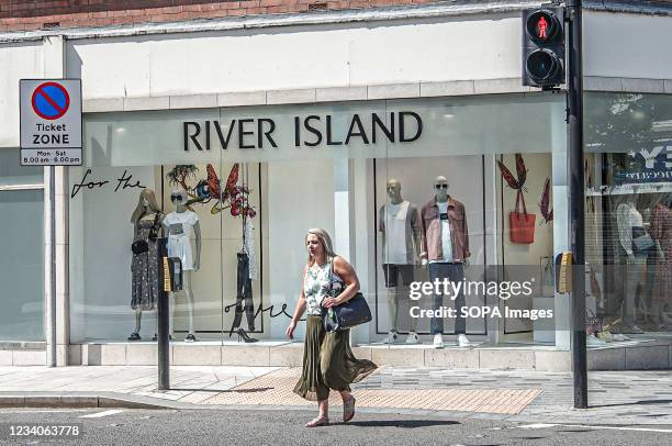Shopper walks in front of River Island Fashion Store on Bow Street.