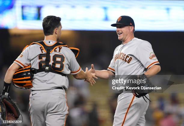 Relief pitcher Jake McGee of the San Francisco Giants celebrates with catcher Buster Posey after defeating the Los Angeles Dodgers, 7-2, at Dodger...